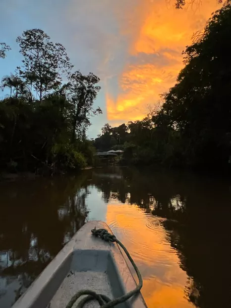 Orange sunset seen from a canoe on a calm river