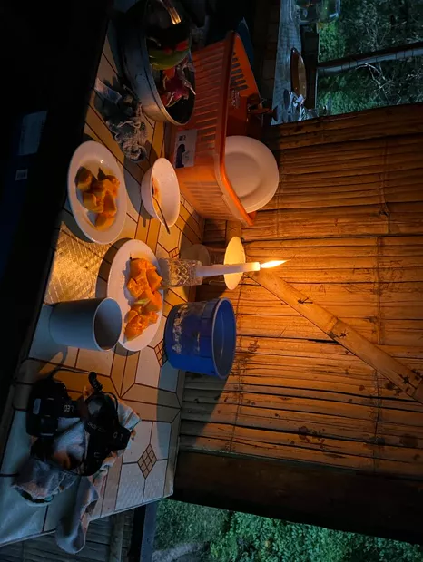Candlelit dinner table on the porch of a bamboo cabin