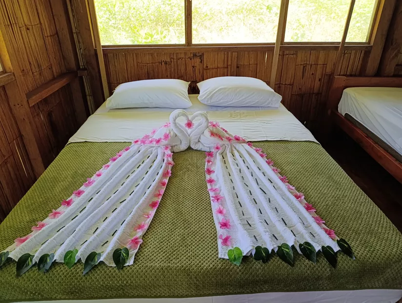 Beds decorated with towel swans on a blue runner
