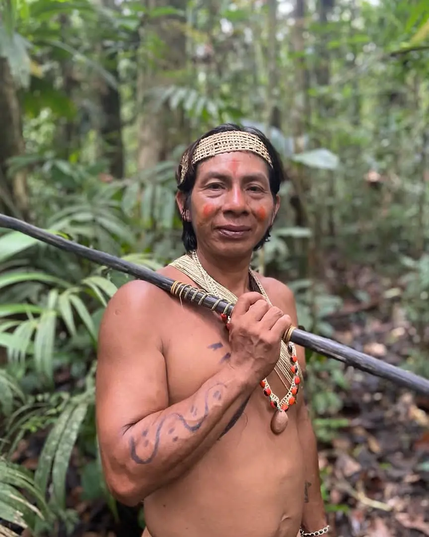 Waorani guide wearing a woven crown and holding a blowgun in the Shiripuno forest