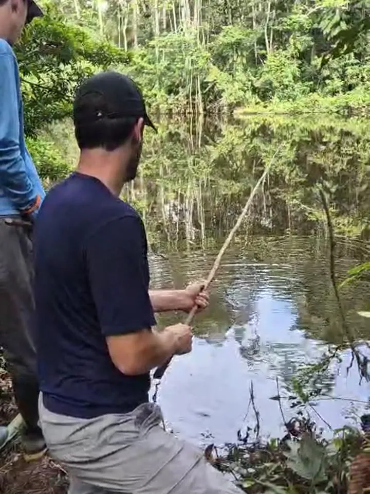 Visitor fishing for piranhas with a handmade rod in a Shiripuno lagoon