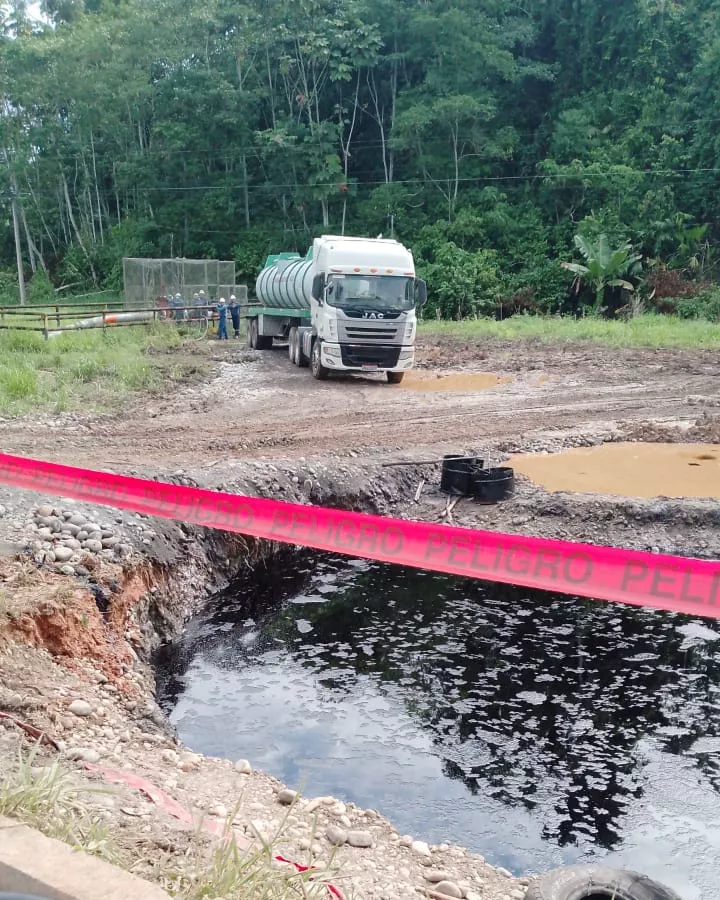 Crude oil pit cordoned off with hazard tape next to a tanker truck in an oil field